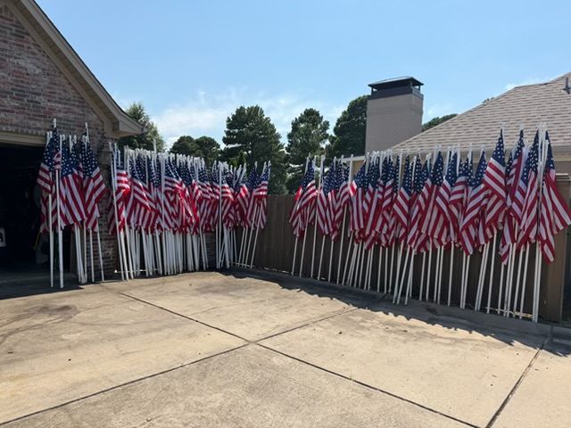 Rows of American flags staged in a driveway before installation