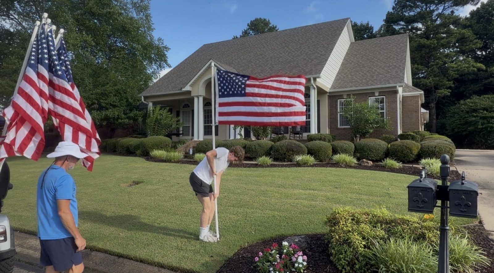 Neighbors installing American flags on a front lawn